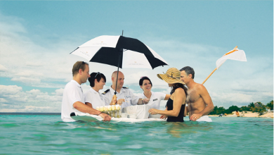 Guests in a sea getting looked after by a crew holding an umbrella